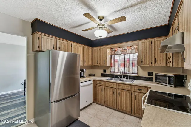 a kitchen with stainless steel appliances granite countertop a sink a stove a refrigerator cabinets and a window