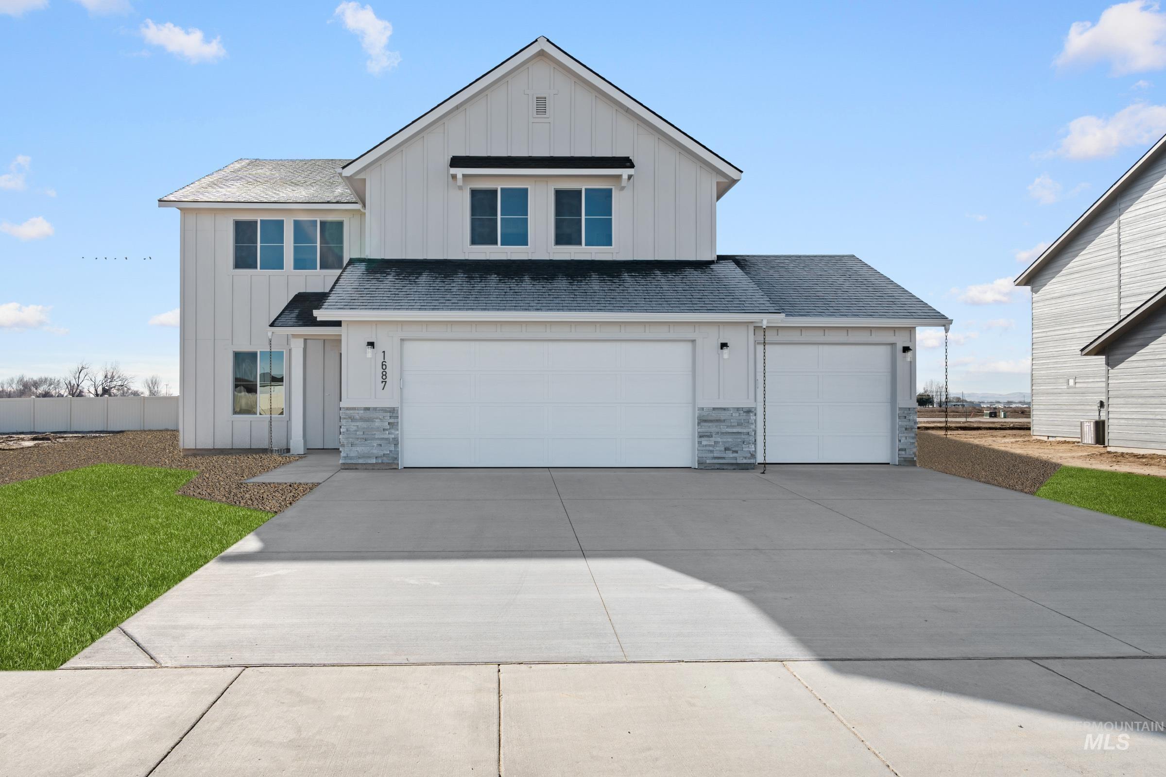 View of front of home featuring board and batten siding, driveway, stone siding, and a shingled roof
