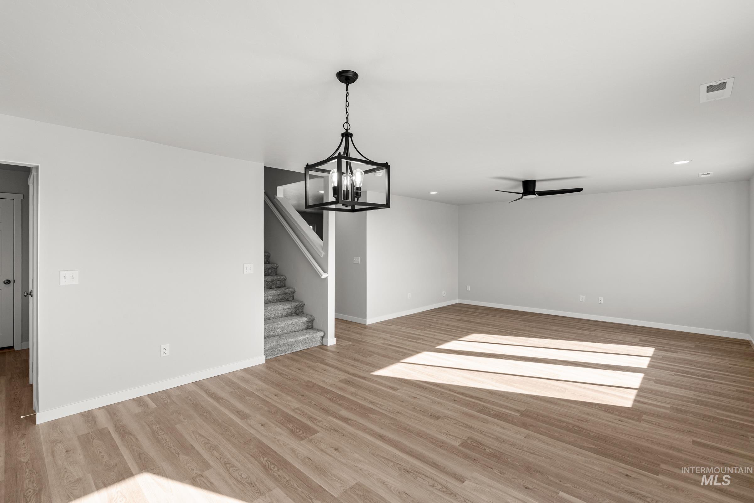 1687 Dyer Street Middleton, ID 83644 - Photo 7 of 28 Unfurnished living room featuring a ceiling fan, light wood finished floors, and suspended lighting