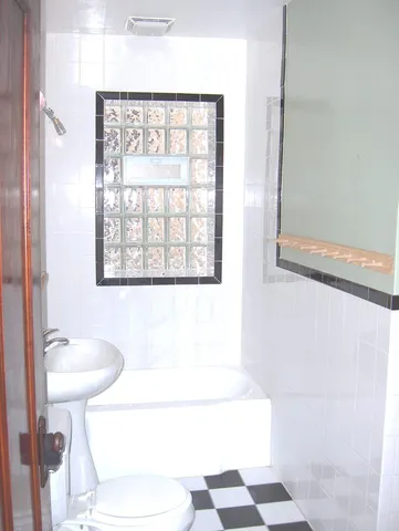 a bathroom with a sink a toilet a window and shower