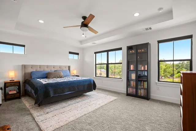 a spacious bedroom with a bed a dresser and a large window