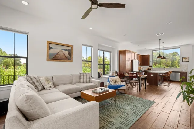 a living room with furniture large window and kitchen view