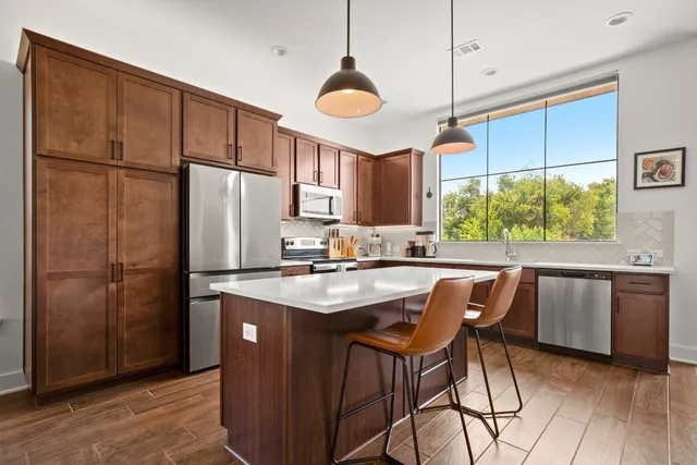 a kitchen with kitchen island a counter space a sink appliances and cabinets