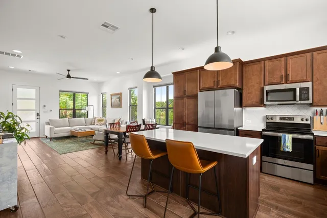 a open kitchen with stainless steel appliances granite countertop a stove a kitchen island a dining table and chairs