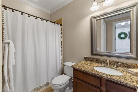 a bathroom with a granite countertop sink vanity mirror and a toilet