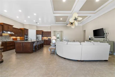 a living room with couches a flat screen tv and kitchen view