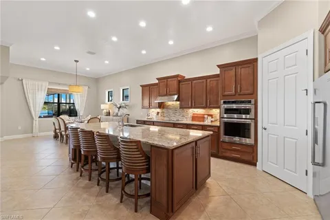 a kitchen with stainless steel appliances granite countertop a table chairs sink refrigerator and cabinets