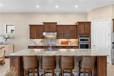 a kitchen with stainless steel appliances granite countertop a table chairs in it and wooden floors