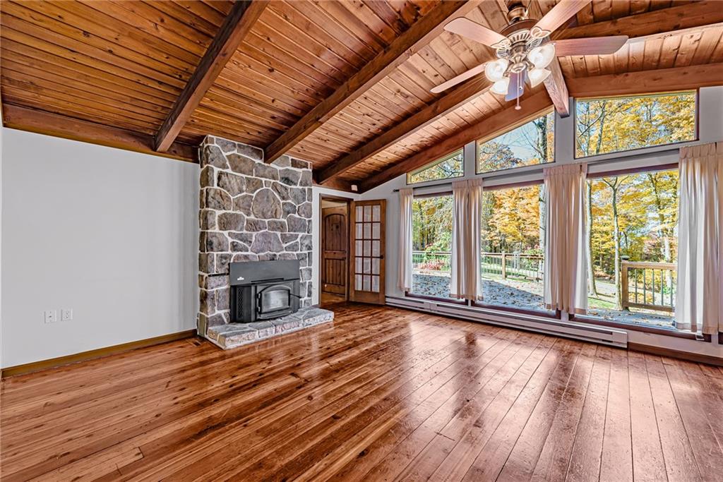 149 Maple Road Acme, PA 15610 - Photo 4 of 25 an empty room with wooden floor fireplace and windows