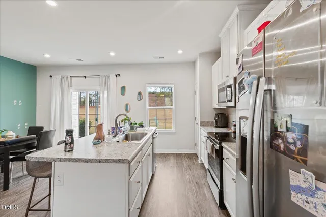 a dining hall with stainless steel appliances granite countertop a dining table and chairs with wooden floor