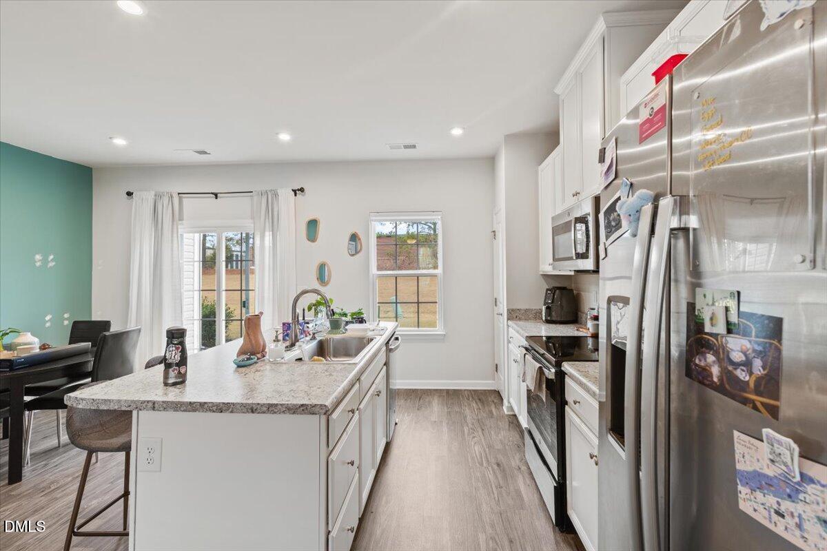 8721 Red Canyon Way Raleigh, NC 27616 - Photo 7 of 29 a dining hall with stainless steel appliances granite countertop a dining table and chairs with wooden floor