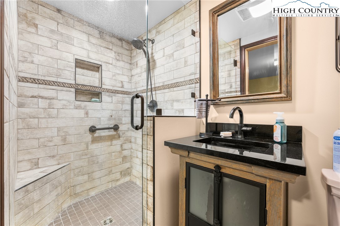 615 Sampson Road Boone, NC 28607 - Photo 21 of 36 a bathroom with a granite countertop sink a mirror and shower