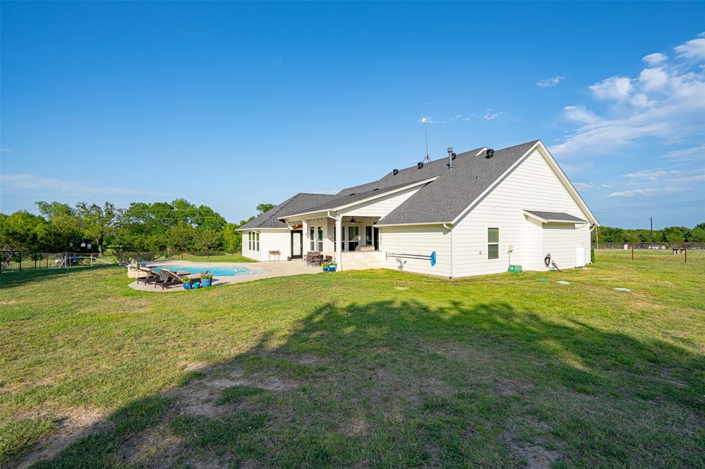 1920 Meander Road Granbury, TX 76049 - Photo 29 of 40 Expansive backyard featuring a built-in swimming pool with a surrounding paved deck, white siding exterior, and a dark shingle roof