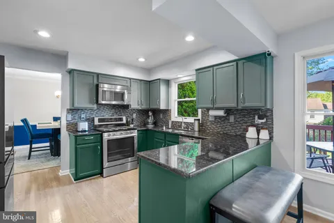 a kitchen with stainless steel appliances granite countertop a stove a sink a microwave a refrigerator and cabinets