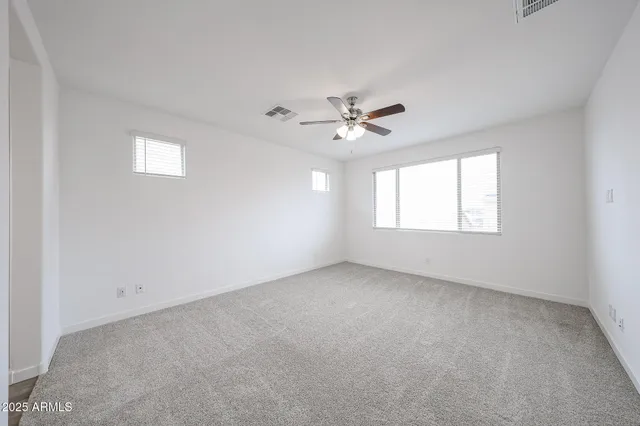 an empty room with windows and ceiling fan