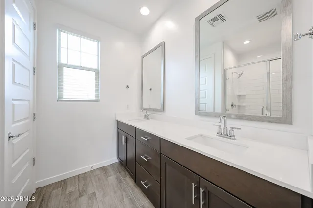 a bathroom with double vanity sink a mirror and a shower