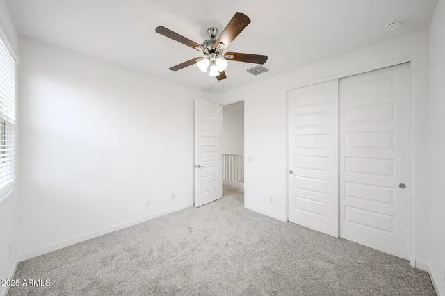 an empty room with closet and fan