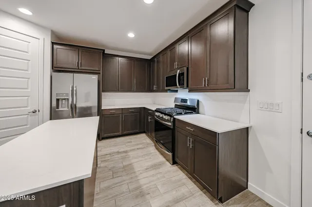 a large kitchen with stainless steel appliances kitchen island granite countertop a stove a refrigerator and a sink with wooden cabinets