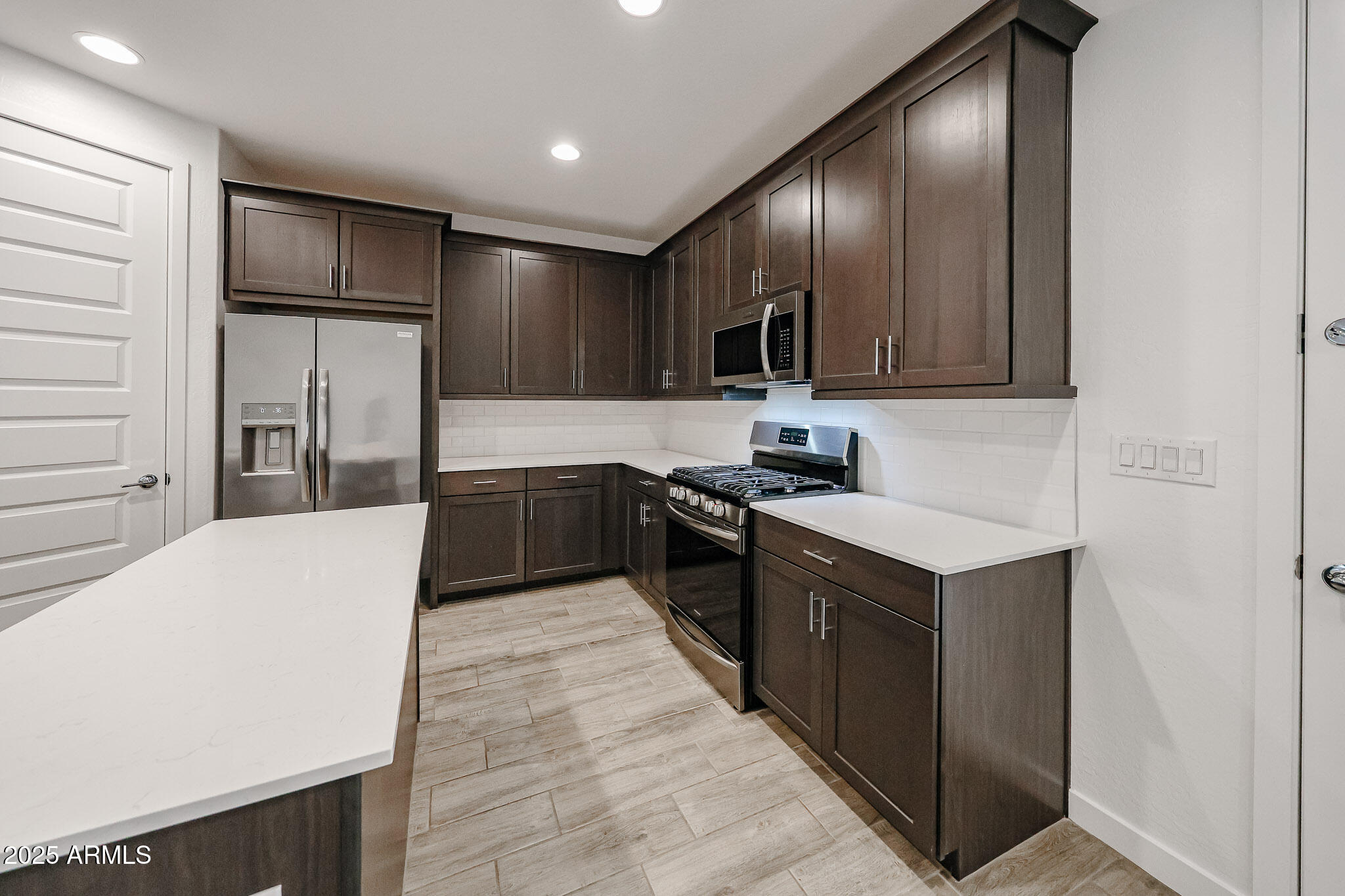 12526 West Morten Avenue Glendale, AZ 85307 - Photo 2 of 27 a large kitchen with stainless steel appliances kitchen island granite countertop a stove a refrigerator and a sink with wooden cabinets
