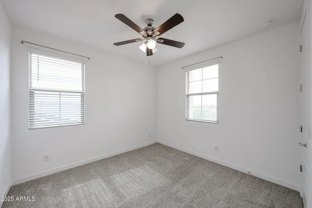 an empty room with ceiling fan and windows