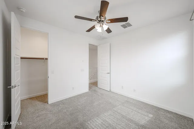 an empty room with a ceiling fan and carpet