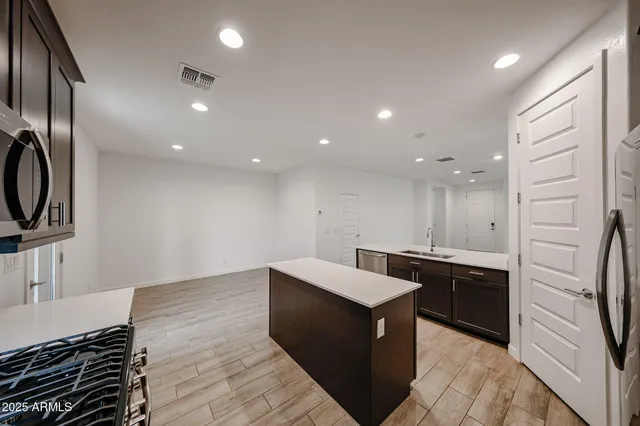 a large kitchen with stainless steel appliances a large counter top a stove and a refrigerator