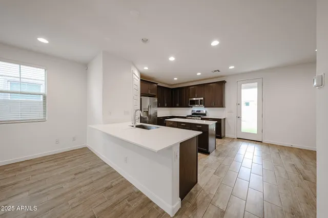 a kitchen with stainless steel appliances kitchen island hardwood floor sink stove and wooden cabinets