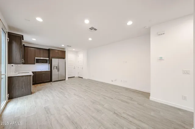 a view of a big room with wooden floor and a kitchen
