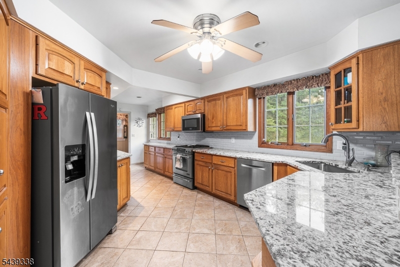 1 Oak Grove Road Flemington, NJ 08822 - Photo 10 of 29 a large kitchen with stainless steel appliances granite countertop a refrigerator a sink dishwasher a stove with wooden cabinets and floor