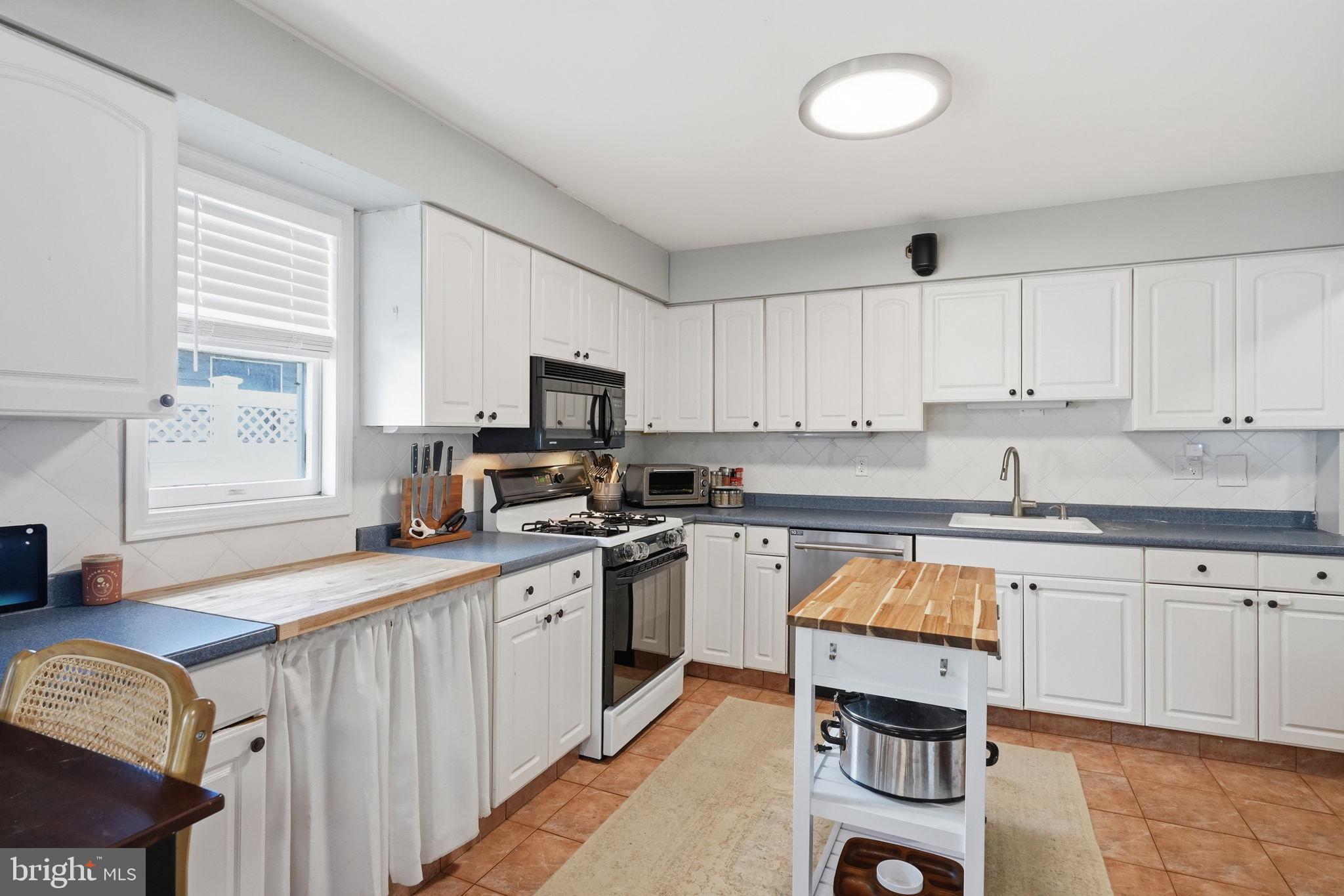 15 Deans Rhode Hall Road Monmouth Junction, NJ 08852 - Photo 11 of 24 a kitchen with stainless steel appliances granite countertop a stove top oven a sink dishwasher and white cabinets with wooden floor