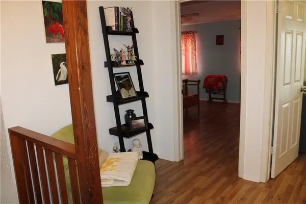 a view of a hallway with wooden floor and a livingroom with furniture