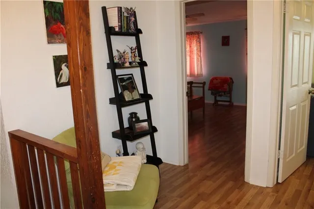a view of a hallway with wooden floor and a livingroom with furniture