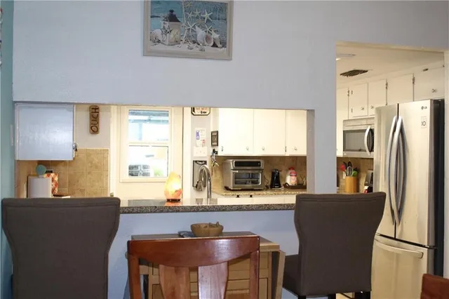 a kitchen with stainless steel appliances granite countertop a refrigerator a stove a sink dishwasher and white cabinets with wooden floor