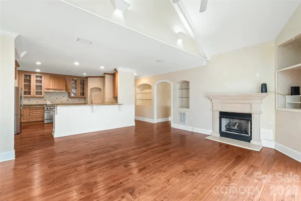 a view of a big room with wooden floor and a kitchen