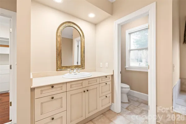 a spacious bathroom with a granite countertop toilet a sink and mirror