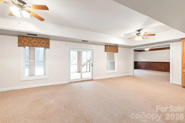 an empty room with windows and chandelier fan