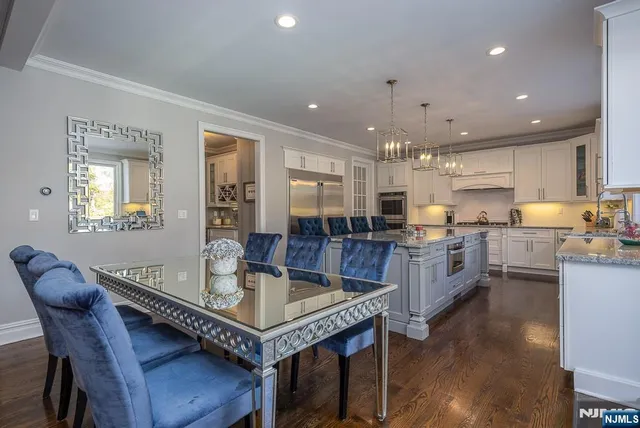 a kitchen with stainless steel appliances granite countertop a stove a refrigerator a kitchen island a dining table and chairs