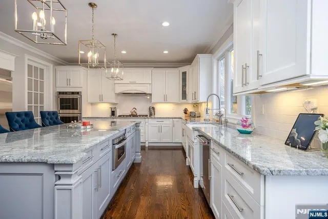 a kitchen with kitchen island granite countertop a sink a counter space appliances and cabinets