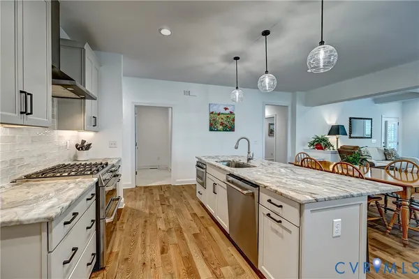 a kitchen with a stove a sink a refrigerator and a wooden floor