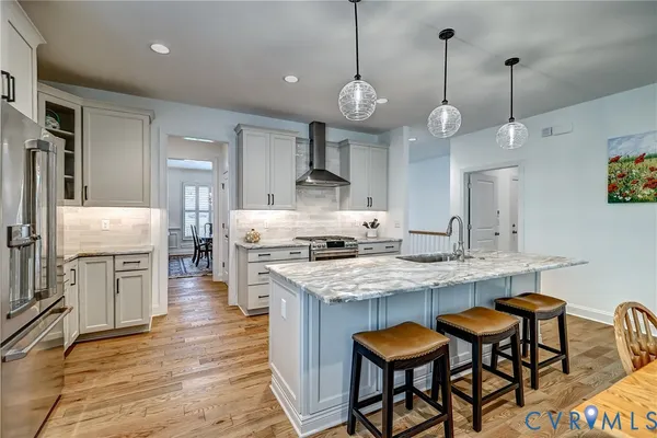 a open kitchen with stainless steel appliances granite countertop a stove a sink a oven a dining table and chairs with wooden floor