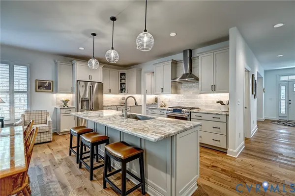 a large kitchen with stainless steel appliances granite countertop a stove a refrigerator a oven a dining table and chairs with wooden floor