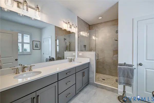 a bathroom with a double vanity sink mirror and shower