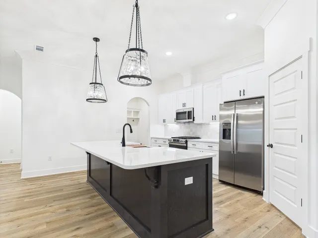a kitchen with stainless steel appliances granite countertop a sink a stove and refrigerator