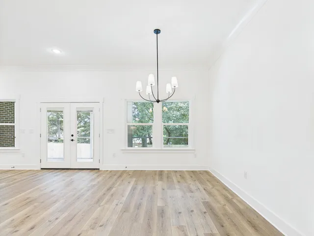 a view of an empty room with wooden floor and windows