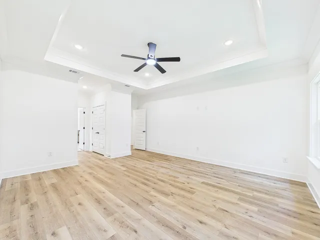 an empty room with windows and a ceiling fan