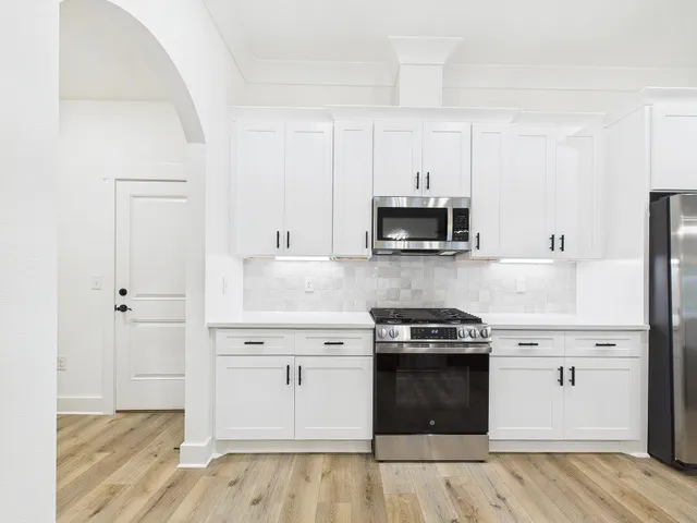 a kitchen with stainless steel appliances a table chairs and cabinets