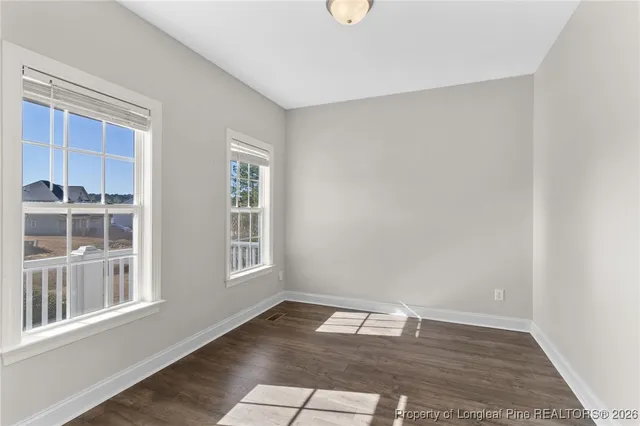 a view of an empty room with wooden floor and windows