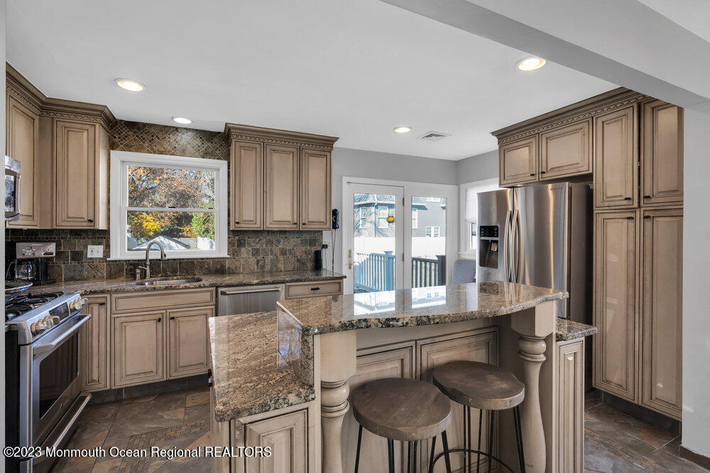 17 Eisele Avenue Asbury Park, NJ 07712 - Photo 32 of 52 a kitchen with stainless steel appliances granite countertop a stove a refrigerator a sink dishwasher a dining table and chairs with wooden floor