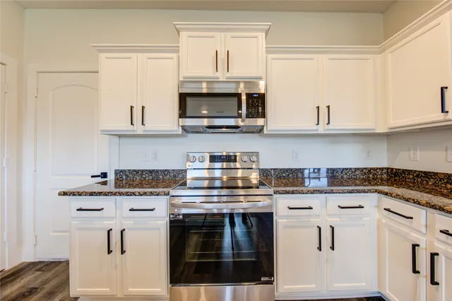 a kitchen with stainless steel appliances granite countertop a stove and white cabinets