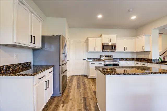 a kitchen with stainless steel appliances granite countertop a stove a sink and a refrigerator